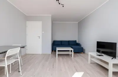 a living room with a blue couch and a table at Osiedle Kombatantów Standard Apartment by BookingHost in Kraków