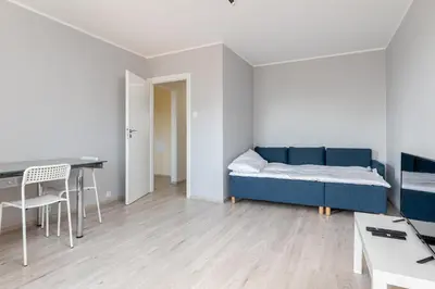 a living room with a blue couch and a desk at Osiedle Kombatantów Standard Apartment by BookingHost in Kraków