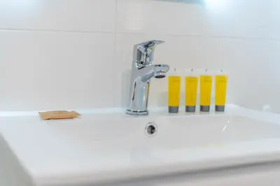 a sink with a faucet and some yellow glasses at Osiedle Kombatantów Standard Apartment by BookingHost in Kraków