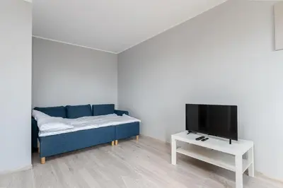 a living room with a blue couch and a tv at Osiedle Kombatantów Standard Apartment by BookingHost in Kraków