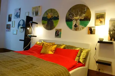 a bedroom with a bed with red pillows and clocks on the wall at Sebastian Gold in Kraków