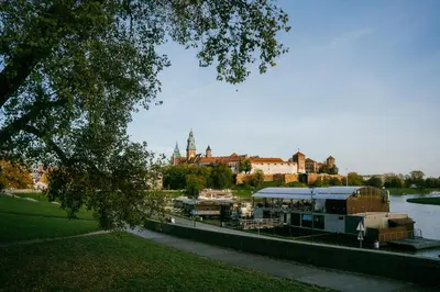 a river with boats docked next to a city at Old Town Zamkowa vis a vis Wawelu in Kraków