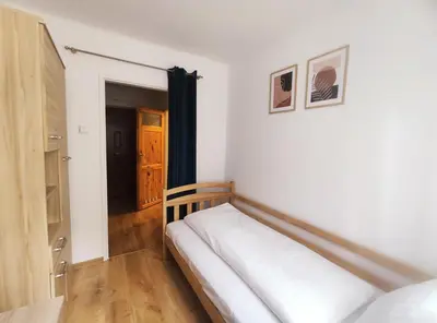 a bedroom with a white bed and a wooden floor at Pielęgniarek 5 by Homeprime in Kraków