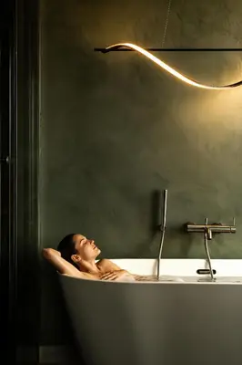 a woman laying in a bath tub with a lamp at Rooftop Apartment with Terrace by T in Kraków