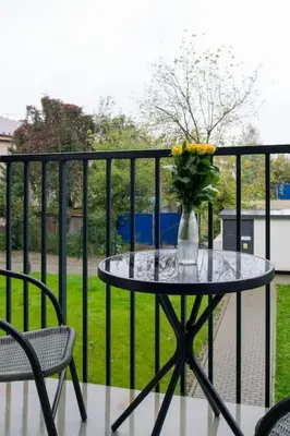 a table with a vase of flowers on a balcony at In Gold Apartment in Kraków