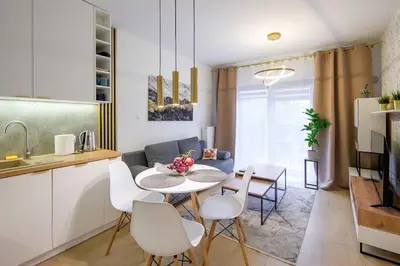 a kitchen and a living room with a table and chairs at In Gold Apartment in Kraków