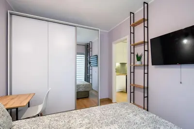 a bedroom with a sliding glass door with a tv at In Gold Apartment in Kraków