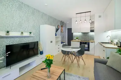 a living room with a tv and a kitchen with a table at In Blue Apartment in Kraków