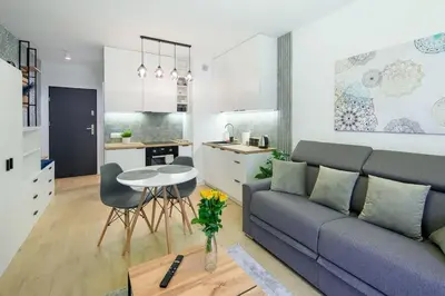 a living room with a couch and a table and a kitchen at In Blue Apartment in Kraków