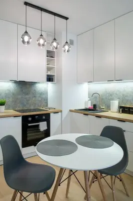 a white kitchen with a table and two chairs at In Blue Apartment in Kraków