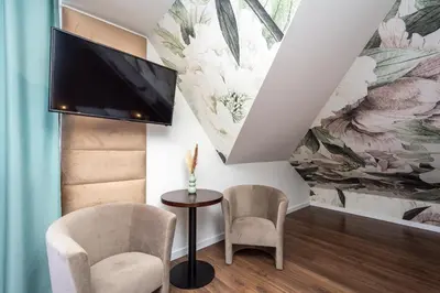 a living room with a tv and two chairs and a table at Hotel i Restauracja Stara Kuźnia in Dobczyce