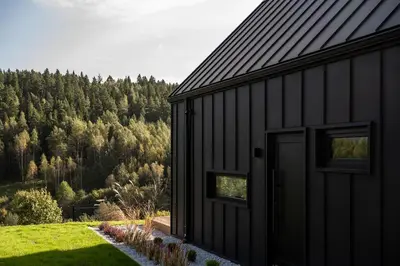 a black house with a view of a forest at NALAS domki z widokiem in Rabka
