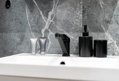 a white sink with three bottles of hair products on it at Malila Premium Apartments Cracow Centre Grzegórzecka 15 in Kraków