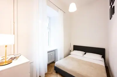 a white bedroom with a bed and a window at Native Apartments Skawińska 5 in Kraków