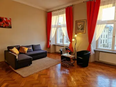a living room with a black couch and red curtains at Royal Palace from the 14th century - 125 m2 in Kraków