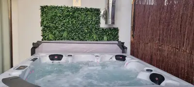 a jacuzzi tub in front of a green wall at Emerald Spa Guest house in Kraków