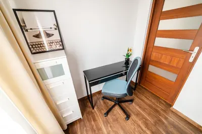 a desk with a blue chair next to a door at Bulwar Kurlandzki Vistula Apartment by BookingHost in Kraków