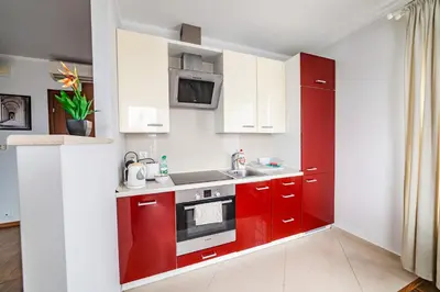 a red kitchen with white cabinets and a sink at Bulwar Kurlandzki Vistula Apartment by BookingHost in Kraków