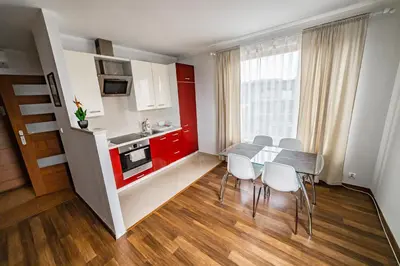 a small kitchen with red cabinets and a table and chairs at Bulwar Kurlandzki Vistula Apartment by BookingHost in Kraków