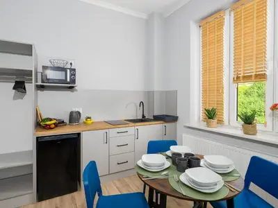 a kitchen with a table and blue chairs at Apartamenty W Centrum Chrzanowa in Chrzanów