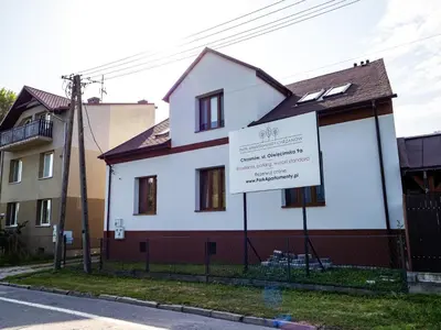 a white house with a sign in front of it at Apartamenty W Centrum Chrzanowa in Chrzanów