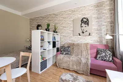 a living room with a pink couch and a brick wall at Negroni Apartments Plac Nowy in Kraków