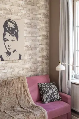 a living room with a pink couch and a brick wall at Negroni Apartments Plac Nowy in Kraków