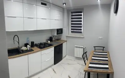a kitchen with white cabinets and a wooden table at Apartament ,,Eden” in Zator