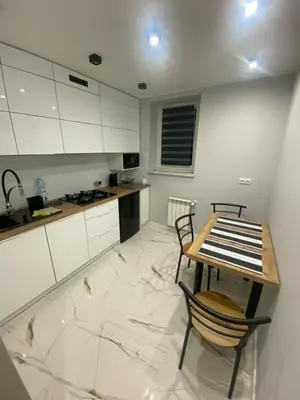a kitchen with white cabinets and a table and chairs at Apartament ,,Eden” in Zator