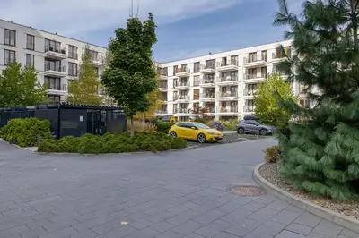 a parking lot with a yellow car parked in front of a building at GO Apartments Studio with Balcony Rakowicka Cracow by Noclegi Renters in Kraków