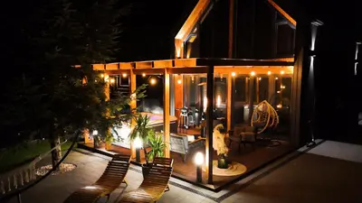 a house with a patio with chairs and lights at Błaż Apart in Laskowa