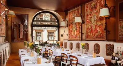 a restaurant with white tables and chairs and a window at Kanonicza 22 in Kraków