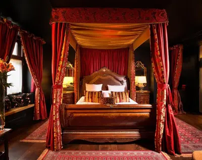 a bedroom with a canopy bed with red curtains at Kanonicza 22 in Kraków