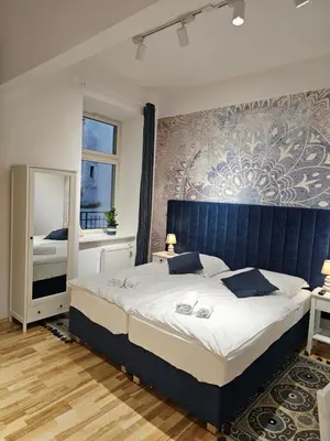 a bedroom with a large bed with a blue headboard at Juwel Apartments Kraków 14 in Kraków