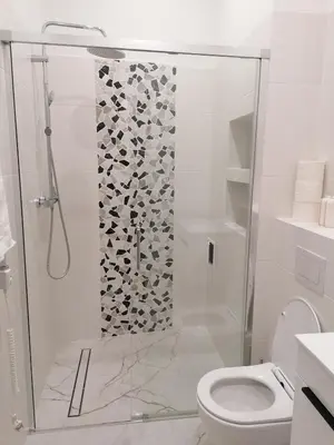 a white bathroom with a shower with a toilet at Juwel Apartments Kraków 14 in Kraków