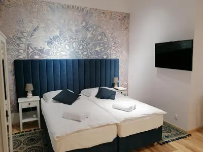 a bedroom with a large bed with a blue headboard at Juwel Apartments Kraków 14 in Kraków