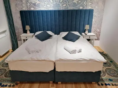a large bed with a blue headboard and two tables at Juwel Apartments Kraków 14 in Kraków