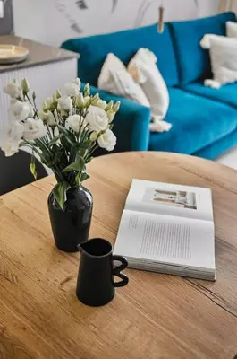 a table with a vase of white flowers and a book at Golden Dreams Luxury Apartments 103 in Kraków