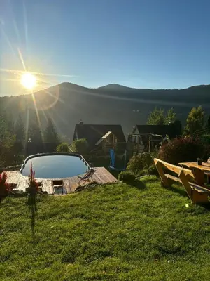 a pool in the middle of a field with the sun at Zawoja Nad Koroną z jacuzzi in Zawoja
