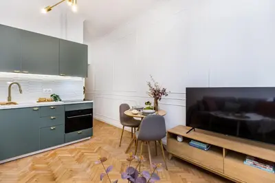 a living room with a table and a kitchen with a tv at Wielopole 7 Apartment 2 rooms in Kraków