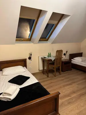 a bedroom with a bed and a table with a chair at Restauracja i Hotel Oberża Wilczy Głód in Krzyszkowice