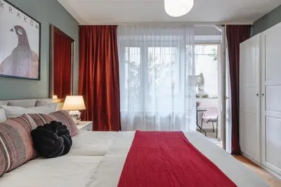 a bedroom with a large white bed with a red blanket at Tomasza 25 Apartament 3 in Kraków