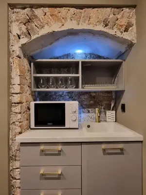 a kitchen with a microwave and a stone wall at Studio Flat With a View in Kraków