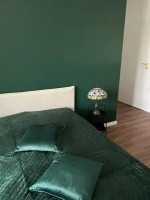 a bed with green pillows and a lamp on a table at Mieszkaj U Marty w GRÓDKU in Jaworzno