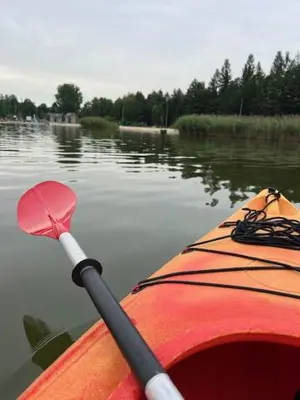 a red kayak with a paddle and a paddle on the water at Mieszkaj U Marty w GRÓDKU in Jaworzno
