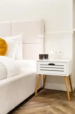 a bed with a white bedside table with a lamp on it at HOUSEHOST Apartment : Sarego Street in Kraków