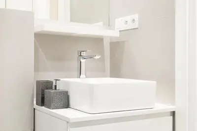 a white bathroom with a sink and a shelf at HOUSEHOST Apartment : Sarego Street in Kraków