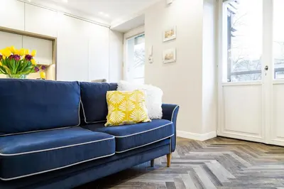 a blue couch in a living room with a vase of flowers at HOUSEHOST Apartment : Sarego Street in Kraków
