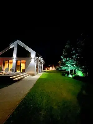 a small house with lights on the side of a yard at Stodoła Chillout Apartments in Marszowice