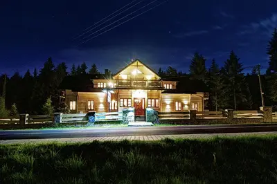 a large wooden house at night with lights at Noclegi Styrnol & SPA in Zawoja